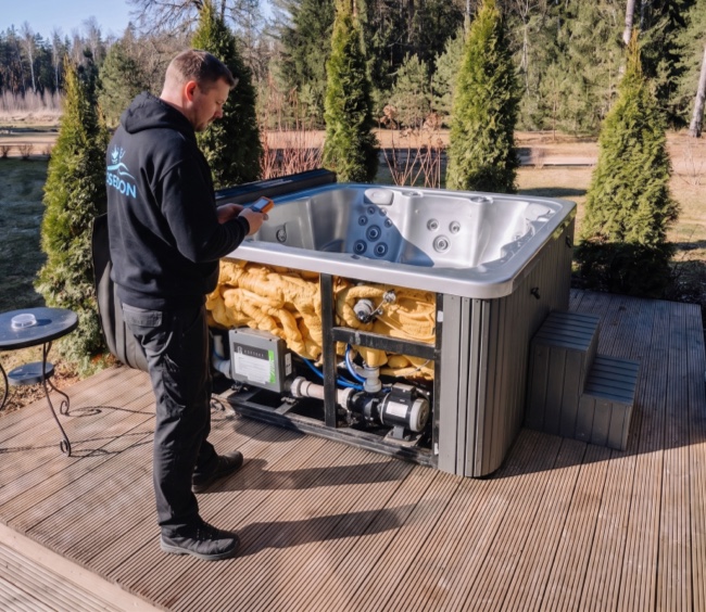 Poseidon technician inspecting the components and plumbing of an outdoor spa during an opening and maintenance service.