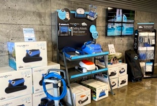 Présentoir de robots nettoyeurs et accessoires pour piscine en magasin spécialisé avec équipements d’entretien et produits disponibles